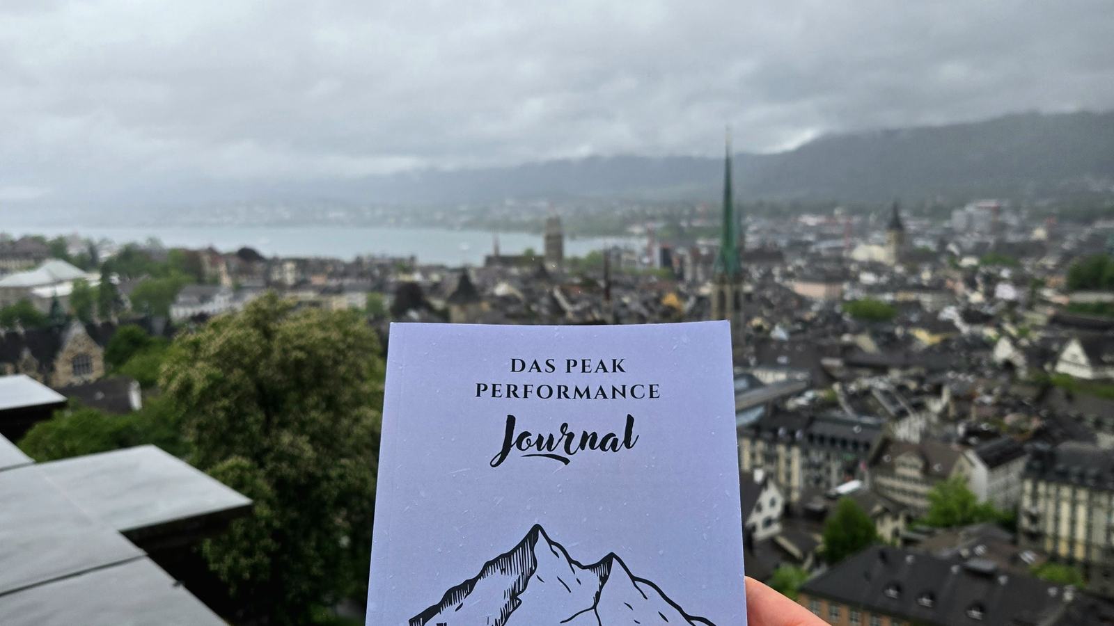 Das Peak Performance Journal, gehalten über der Skyline von Zürich